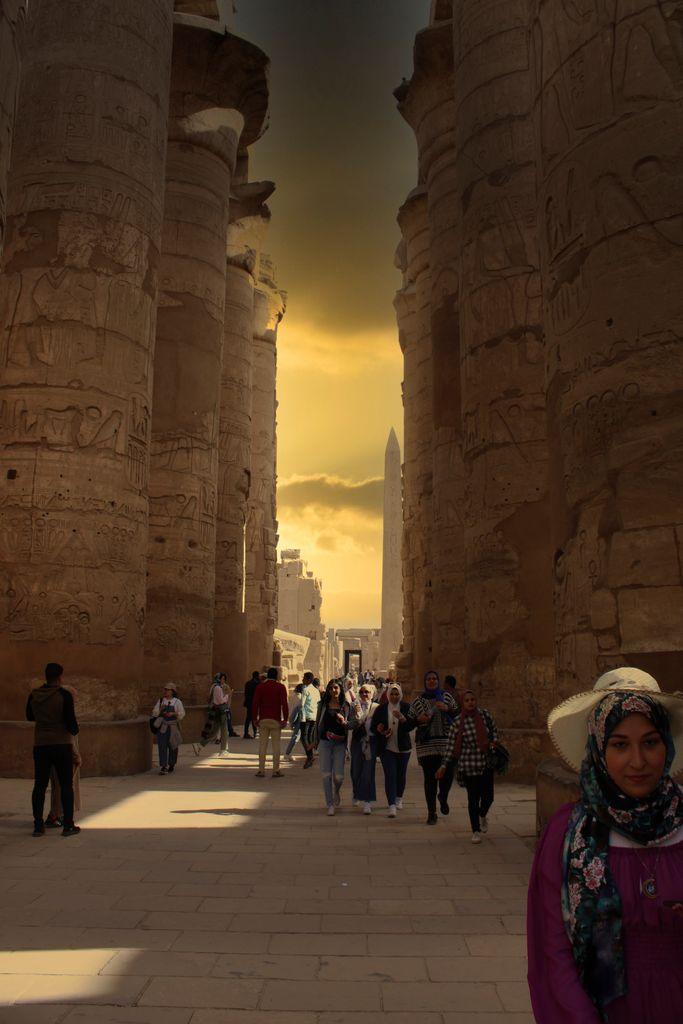Tourists exploring the ancient Karnak Temple in Luxor, Egypt during sunset.